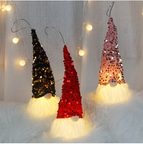 Close-up of sparkling Christmas LED sequin gnomes with warm glowing lights on fur