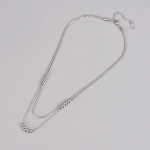 Detail of double-layer silver snake chain necklace with beads and K18 hallmark tag