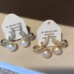 Detailed view of silver and gold bow earrings with S925 silver needles and large pearls