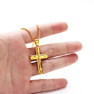 Close-up of golden cross pendant with embossed hip hop patterns held by hand