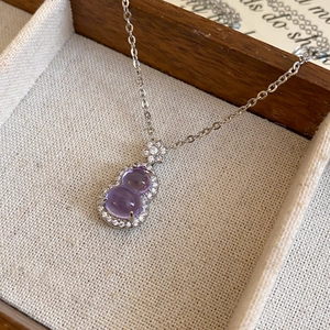 Detailed close-up of a zircon gourd necklace with purple gems in a wooden jewelry box