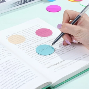 Note adesive tonde trasparenti colorate con penna su un libro per una chiara indicizzazione