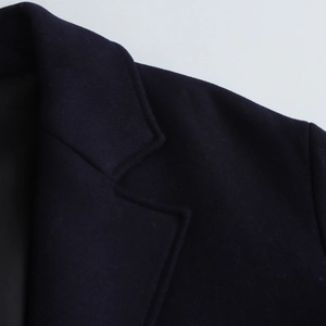 Close-up of dark blue wool coat featuring notch lapel design and premium fabric texture