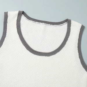 Close-up of white knit vest with grey ribbed trim at U-neckline and sleeve edges