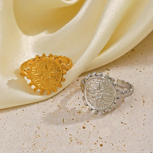Vintage 18K gold and silver plated starburst signet rings on a textured stone base