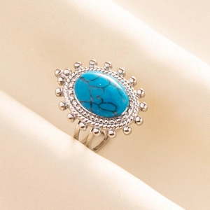 Dettaglio anello bohémien con pietra turchese blu ovale e montatura argentata a raggiera
