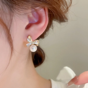 Elegant gold bow earrings with sparkling cubic zirconia and a round white pearl drop