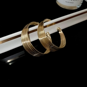 Close-up of textured gold layered hoop earrings on a white stand with a black background
