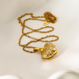 Macro shot of gold shell pendant with zircon and pearl on a polished snake chain