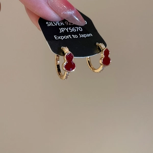 Detail of red enamel gourd earrings in gold finish with sparkling cubic zirconia inlay