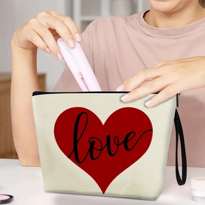 Beige canvas makeup bag with red heart and love print featuring a black wristlet strap