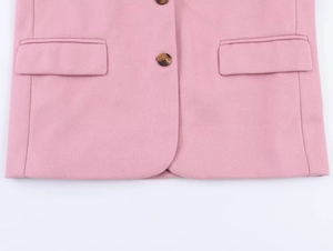 Detail of pink wool blazer showing the flap pocket and brown round button closure