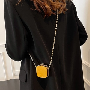 Chic mini gold metallic heart-shaped chain bag worn over a formal black suit