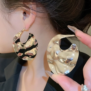 Macro shot of large irregular gold textured metal earrings with crinkled surface