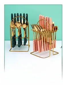 24-piece cutlery set with green and pink ceramic handles on a gold metal storage rack