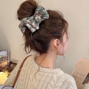 Detail of tweed bow hair clip in grey-green and cream fabric on a bun hairstyle
