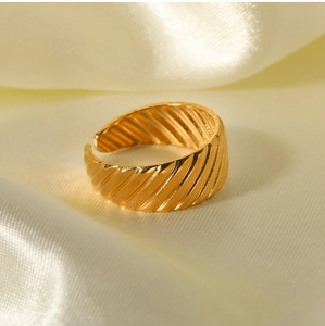 Close-up of golden textured croissant ring on a luxury champagne silk background