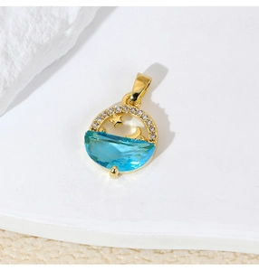 Macro shot of gold dolphin pendant with blue gem and starry moon patterns on white rock