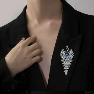 Elegant silver peacock brooch with blue rhinestones pinned on a black suit jacket lapel