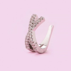 Macro detail of silver-colored cross design ear cuff with sparkling zircon inlay
