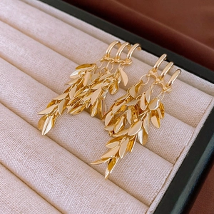 Macro shot of gold leaf tassel earrings with multi-layered wheat spike geometry details