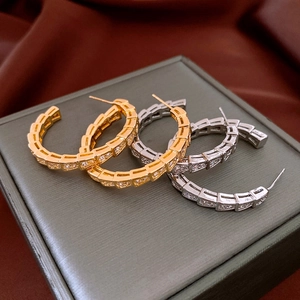 Detail of snake-shaped hoop earrings in gold and silver finish with pavé set crystals