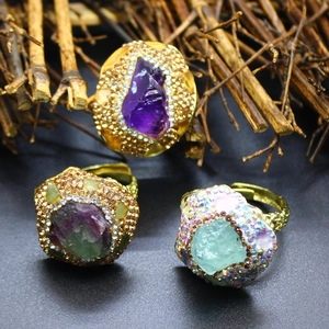 Close-up of three vintage gold rings with raw amethyst and crystals on dark background