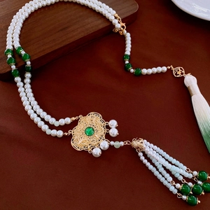 Detail view of neo-Chinese pearl necklace with emerald green gemstone and silk tassels