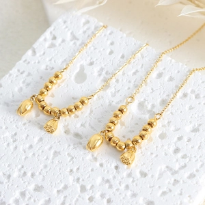 18k gold lotus seed pod anklet in titanium steel displayed on white porous stone decor