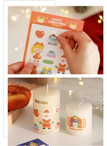 Christmas stickers with Santa and penguin motifs decorating a white DIY candle gift