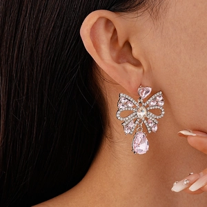 Close-up of bow earrings with pink teardrop crystal on a model's ear