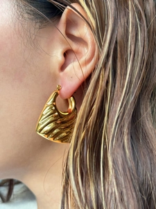 Close-up of golden vintage trapezoid earrings with lava texture on the ear lobe