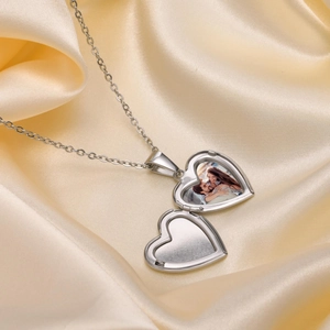 Detail view of a silver heart-shaped locket necklace showing custom photo inside on satin