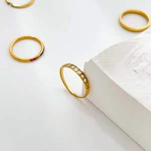 Close-up of gold titanium stackable rings with zircon and star charms on white stone