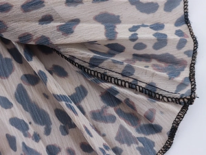 Dettaglio ravvicinato del tessuto chiffon leopardato con cuciture taglia-cuci nere