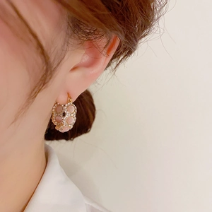 Close-up of elegant gold hoop earrings with pink round stones and crystals on female model