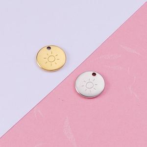 Detailed view of circular gold and silver sun pendants made of mirror-polished titanium steel