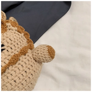 Close-up of handmade crochet texture on beige bear drawstring bag with brown trim