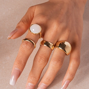 Close-up of gold geometric resin rings set worn by a model on a matte pink background