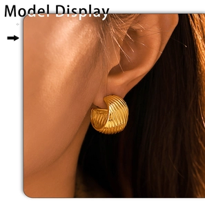 Close-up of model wearing gold-plated C-shaped earrings with textured shell pattern