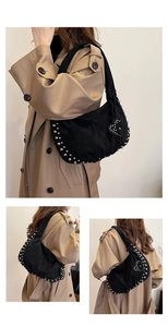 Detail of silver rivets and heart pendant on black matte faux suede crescent bag