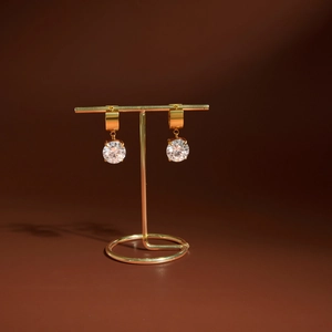 Détail de boucles d'oreilles en zircone ronde dorée sur un support de présentation élégant