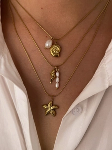 Detail of layered gold necklaces with starfish, conch shell pendants and pearls