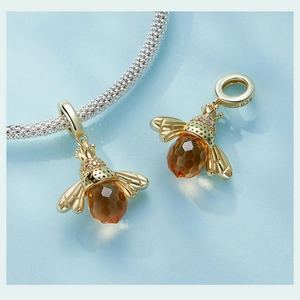 Macro detail of gold S925 bee pendant featuring amber crystal and hallmark engraving
