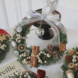 Handcrafted Christmas wreath with pine needles, pinecones, and cinnamon on a display stand