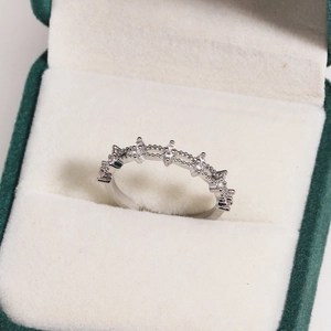 Macro shot of a silver band ring with multiple inlaid white zircons in a green velvet box