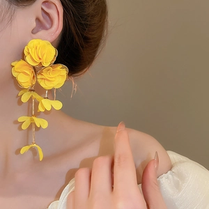 Detail of bright yellow chiffon flower tassel earrings worn on a model for beach style