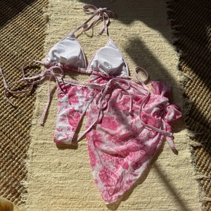 Détail du bikini 3 pièces à fleurs avec paréo et étiquette taille S sur un tapis