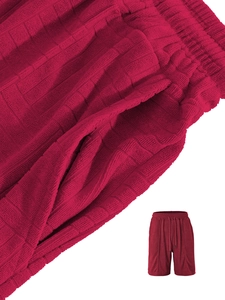 Detail of red waffle knit shorts featuring a drawstring waist and side pocket texture