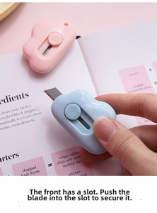 Close-up of mini cloud-shaped utility knives in pink and blue on a magazine